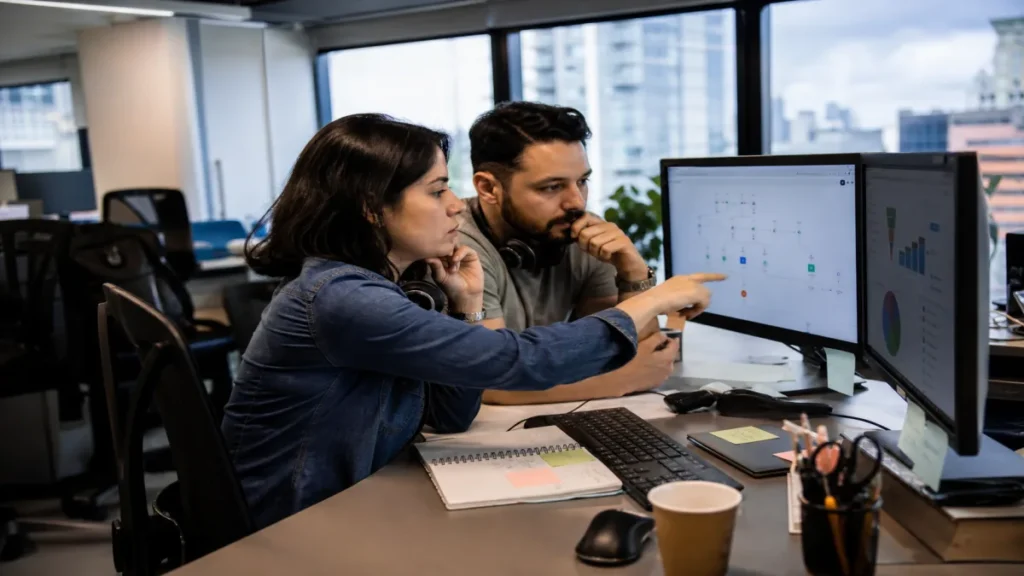 leads para vendas: Analista de marketing revisa fluxo de leads em dashboard de CRM com colega em ambiente de esc.